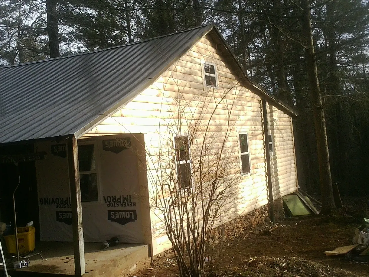 Log siding gable end under a dark metal roof edge in Jesup