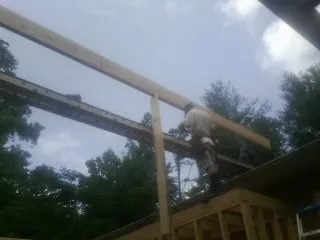 Carpenter setting a ridge beam over a new addition frame — Ice Dam Removal by Roofing Brothers in Jesup