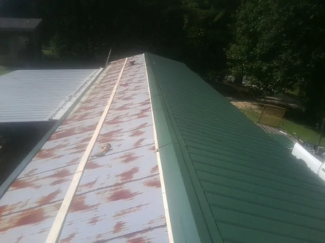 Old rusted panels beside newly installed green metal roofing — Wind Damage Roof Repair by Roofing Brothers in Jesup