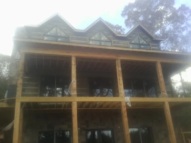 Dormers and porch framing on a large log home under construction — Roof Coating work by our crew in Jesup