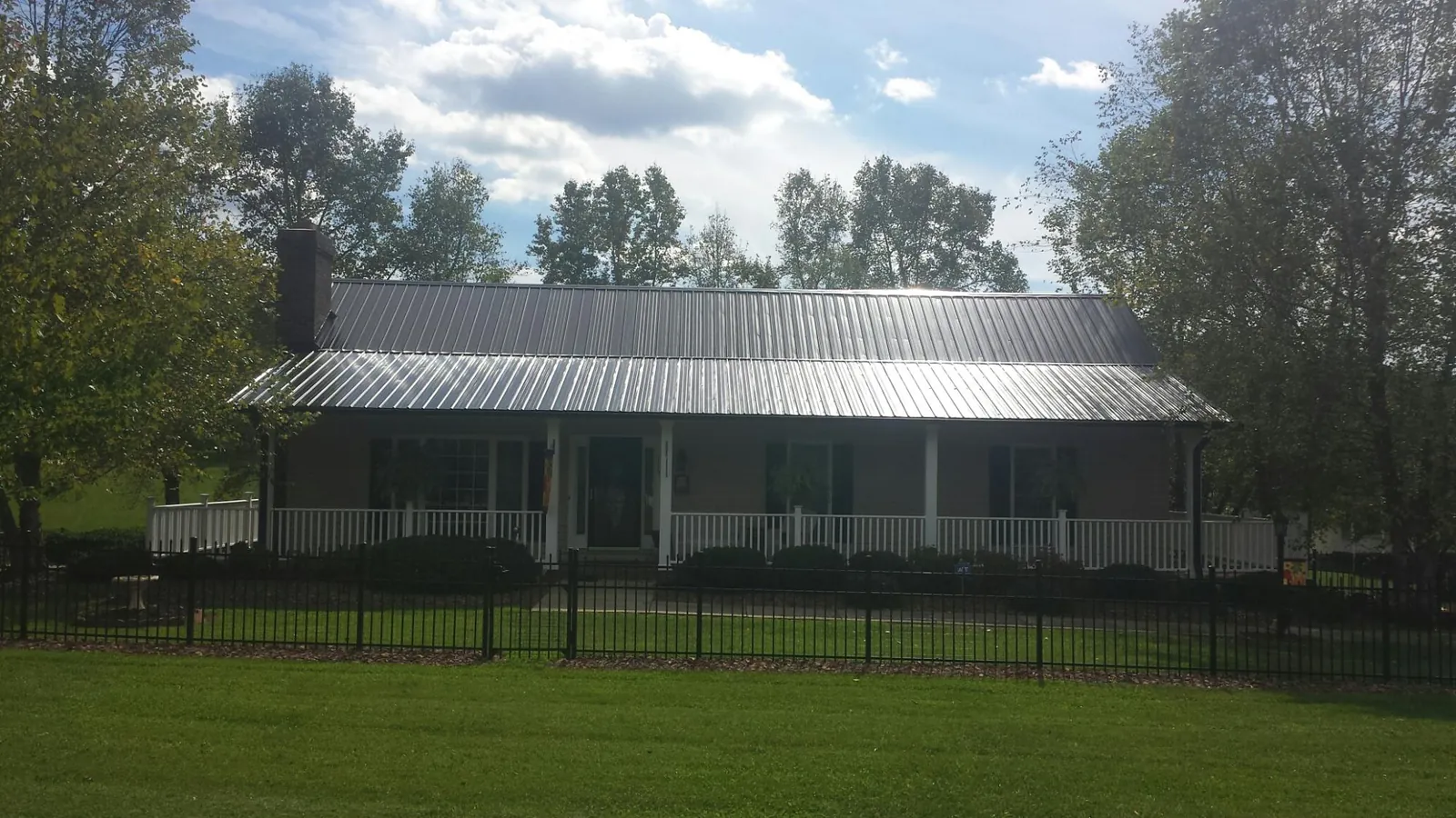Gray metal roof on a brick ranch with a full width front porch — Gutter Guard Installation work by our crew in Jesup